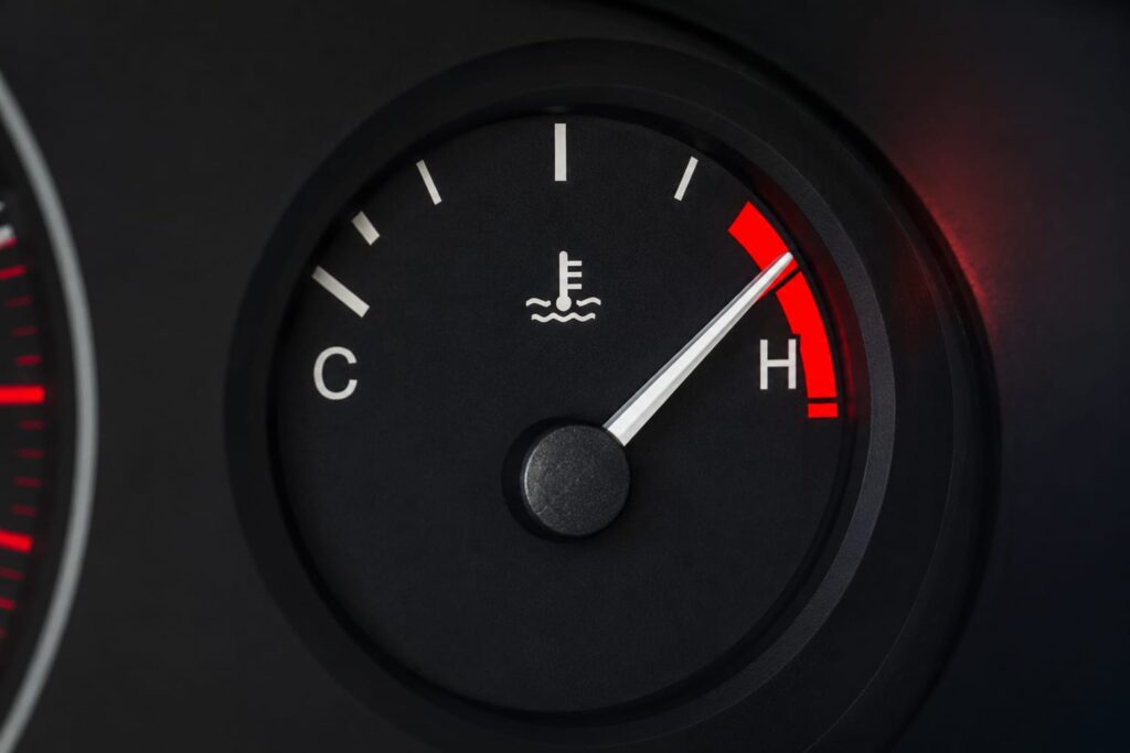 [IMAGE — Dashboard temperature gauge climbing into the red zone. 